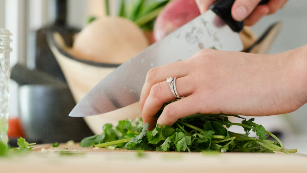 a woman cutting greens on a kitchen counter